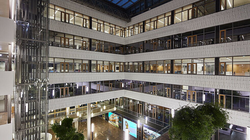 Interior view of the post office building in Luxembourg in the evening with LAMILUX PR60 Passive House glass roof construction and modern atrium.