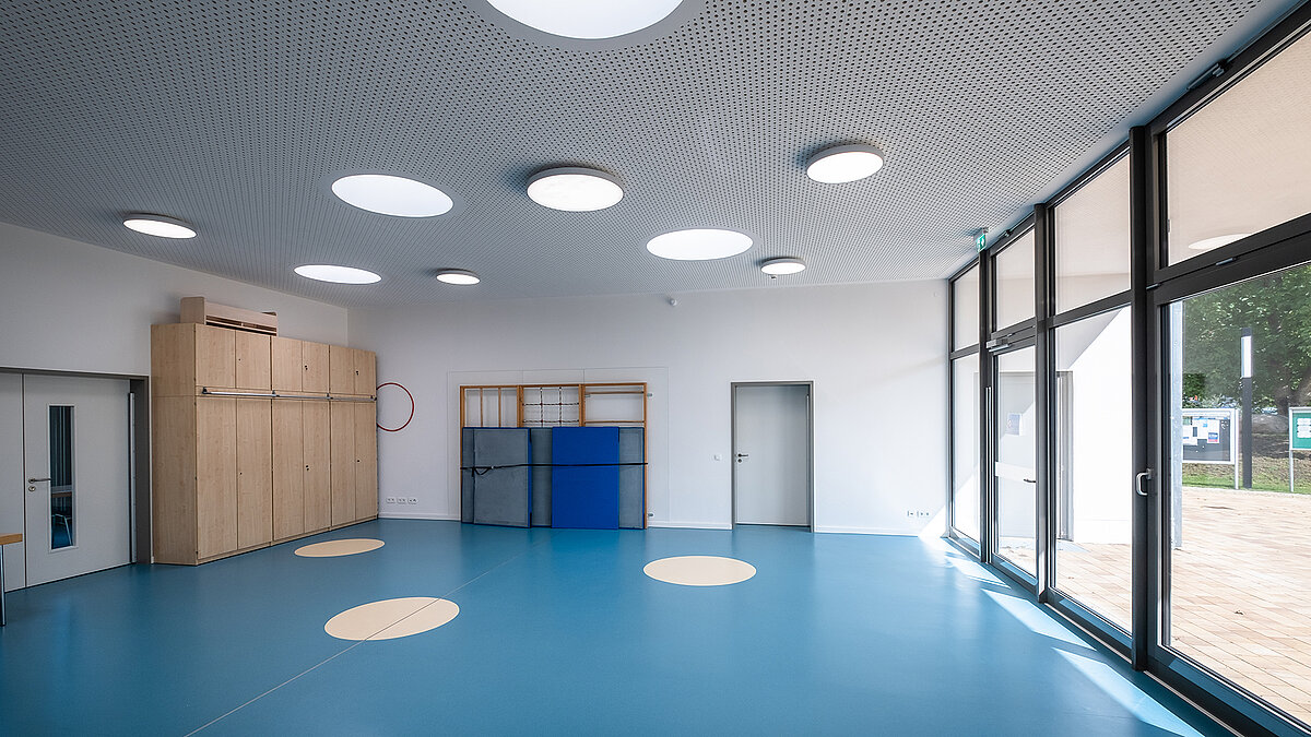 Gymnasium at the Sonnenfeld daycare centre with round skylights on the ceiling and large windows.