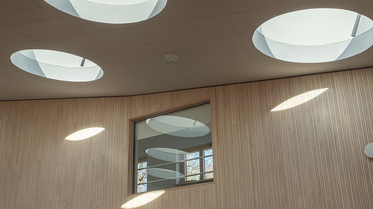 Interior view of round flat roof windows in the St Severin kindergarten, which direct natural light into the interior.