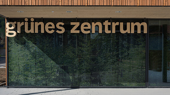 Entrance area of the Green Center Immenstadt with modern glass facade and wooden lettering.