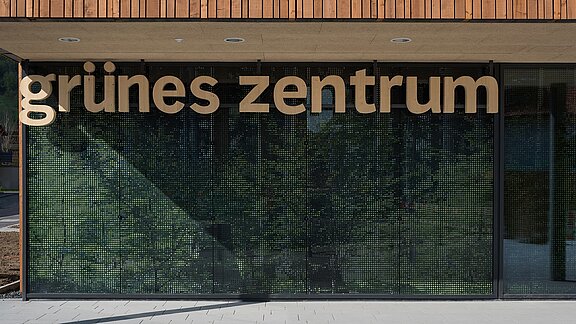Entrance area of the Green Center Immenstadt with modern glass facade and wooden lettering.