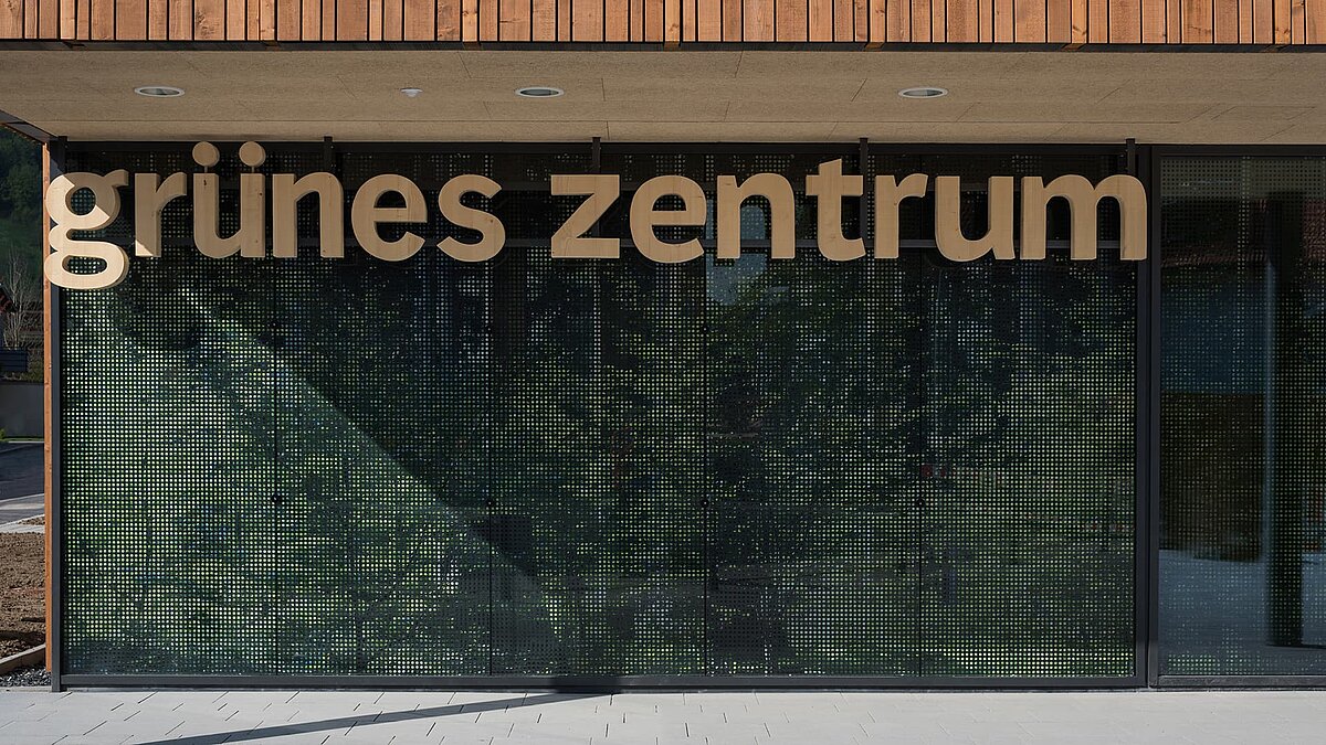 Entrance area of the Green Center Immenstadt with modern glass facade and wooden lettering.