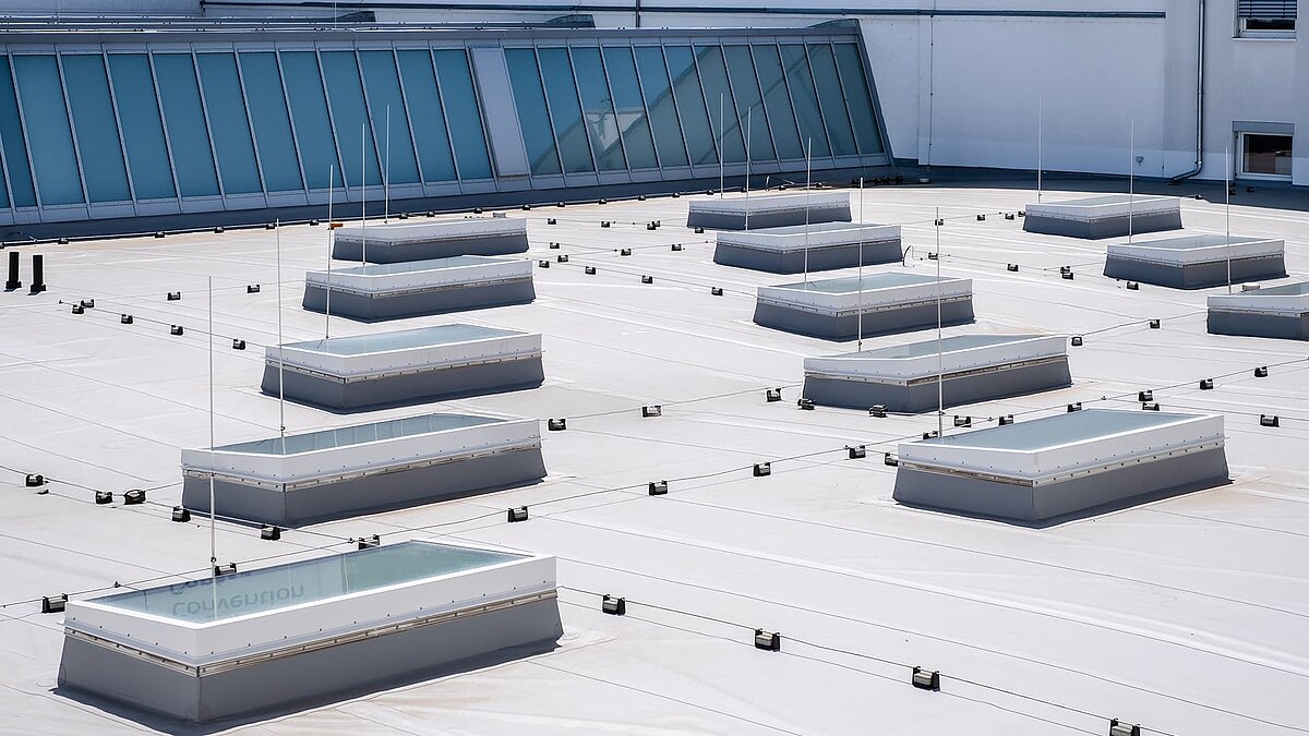 Flat roof of the Vogel Convention Center in Würzburg with multiple flat roof windows and glass roof elements in the background.