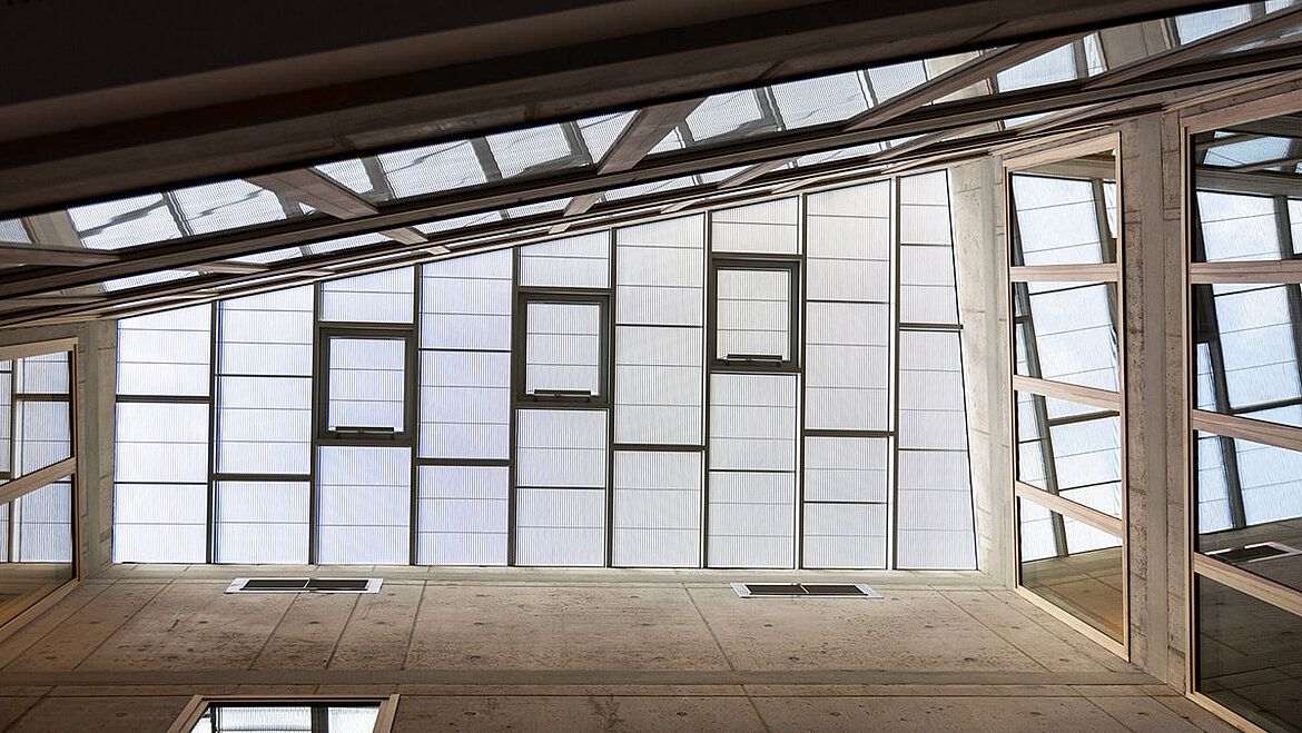 View from below of a glass roof with mirror grids above an inner courtyard