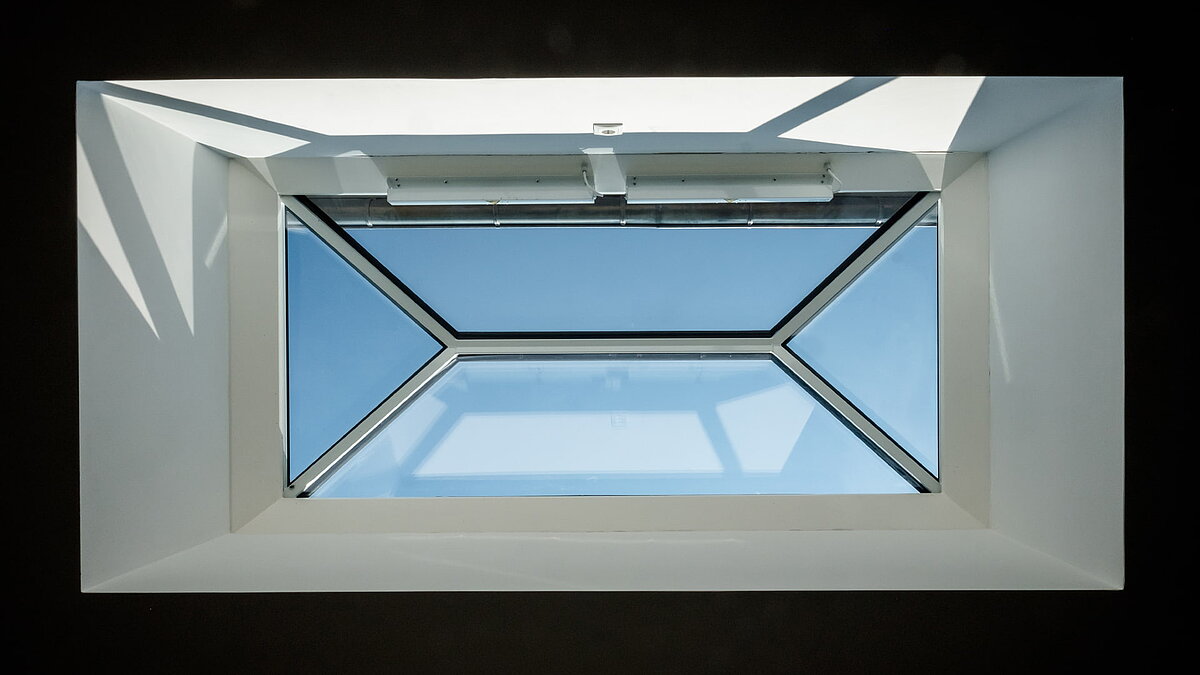 Interior view of a LAMILUX flat roof window FW in a residential house in Hamburg, offering a clear view of the blue sky.