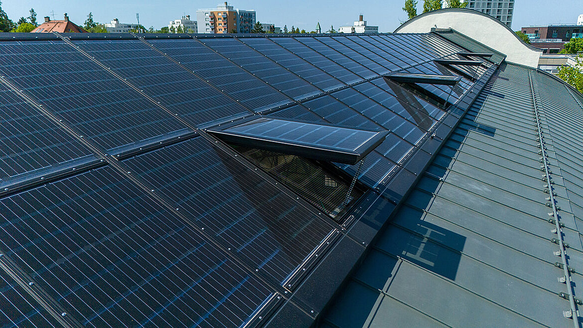 A long roof of an urban building with transparent solar panels.