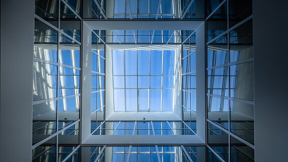 Upward view in the atrium of the Bertha-von-Suttner Realschule in Cologne featuring large glass panels and natural daylight.