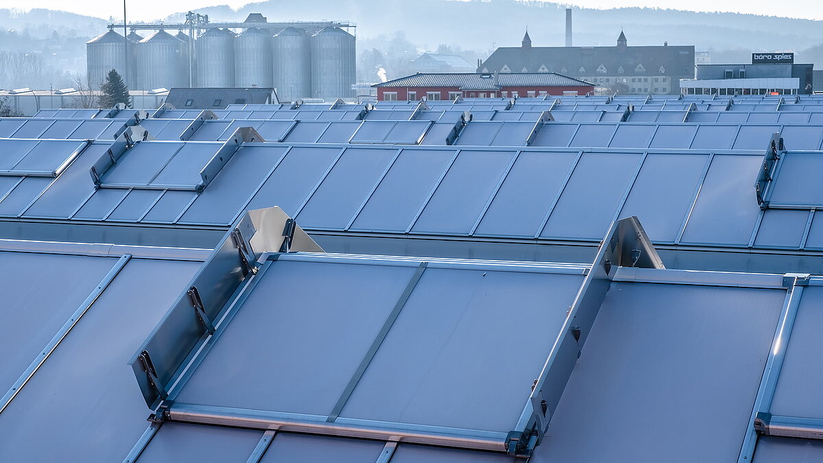 Roof of the OBI hardware store in Bamberg featuring modern skylight panels for natural lighting, with silos and industrial buildings in the background.