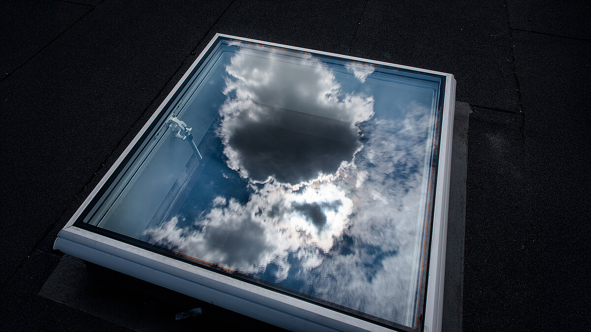 Closed flat roof window on the Caritas building in Hagen, reflecting clouds on the glass.