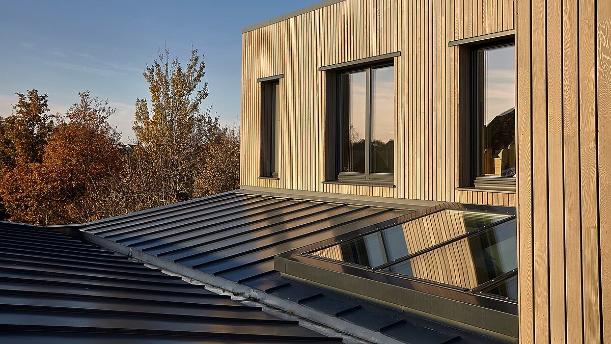 Modern building of Potton Show Homes in England featuring LAMILUX PR60 glass roof and wooden facade in warm evening light.