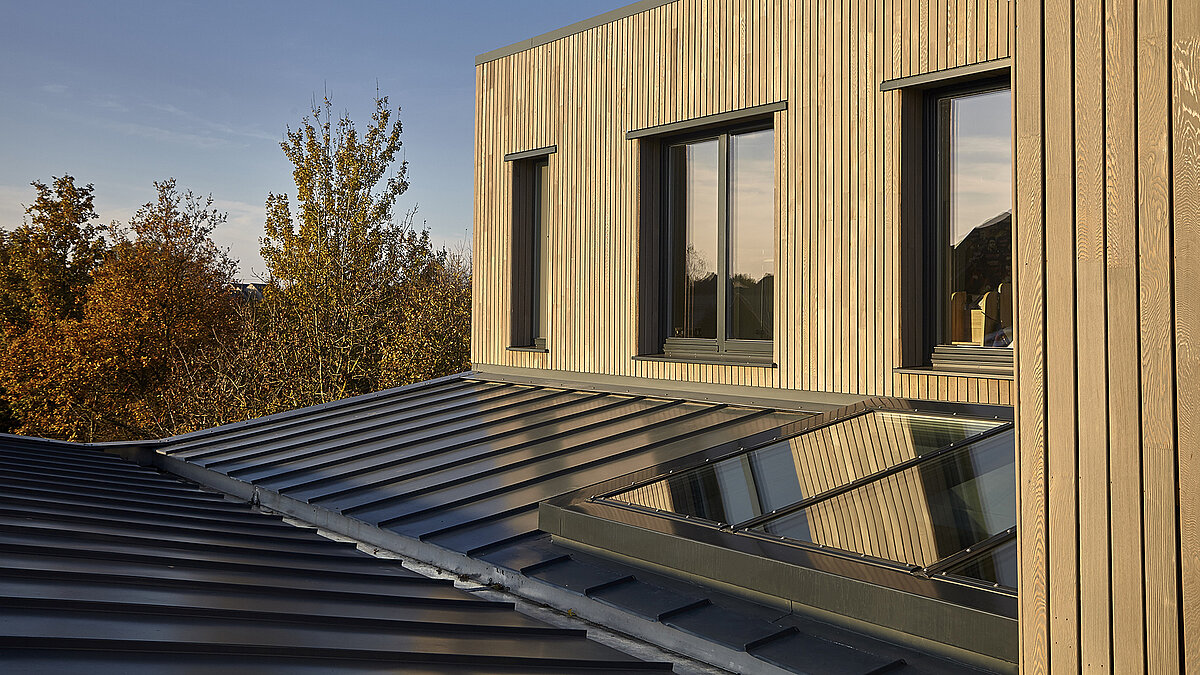 Modern building of Potton Show Homes in England featuring LAMILUX PR60 glass roof and wooden facade in warm evening light.