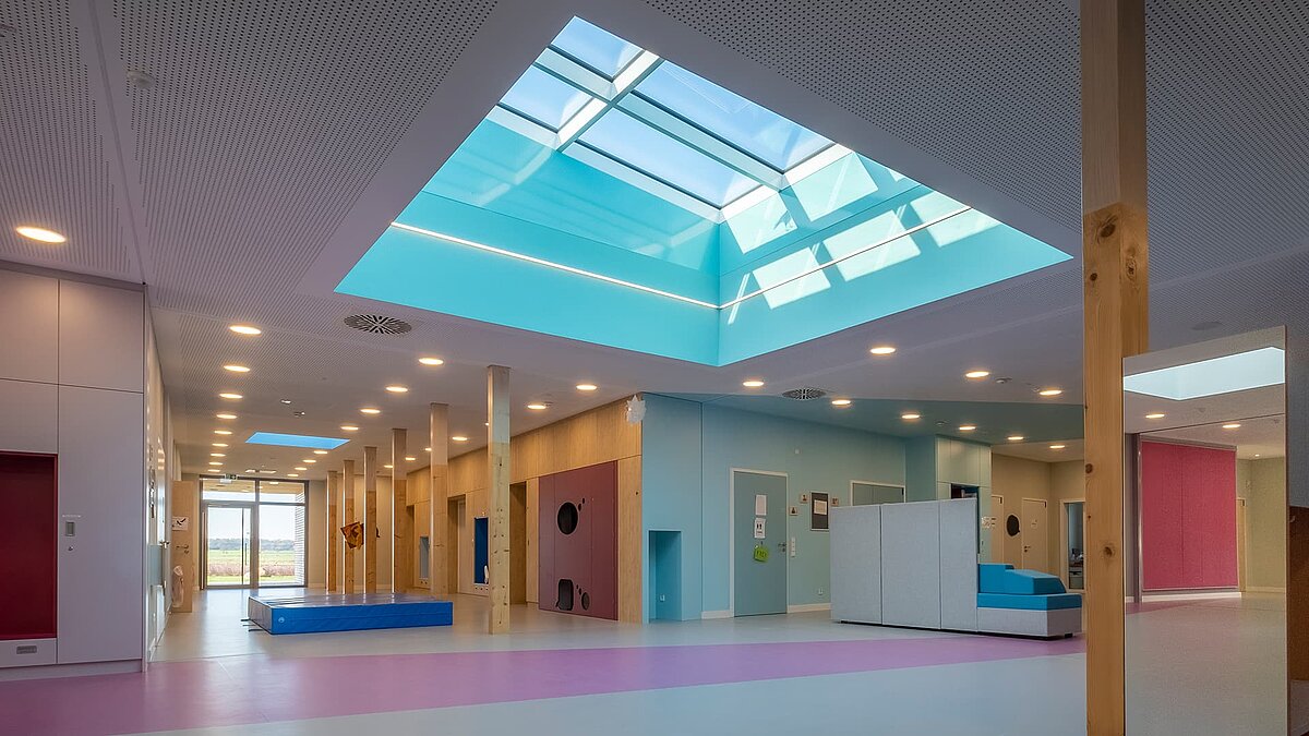 Interior view of the "World of Kids" kindergarten featuring LAMILUX flat roof window FE 3° and PR60 glass roof, creating a bright and welcoming atmosphere.