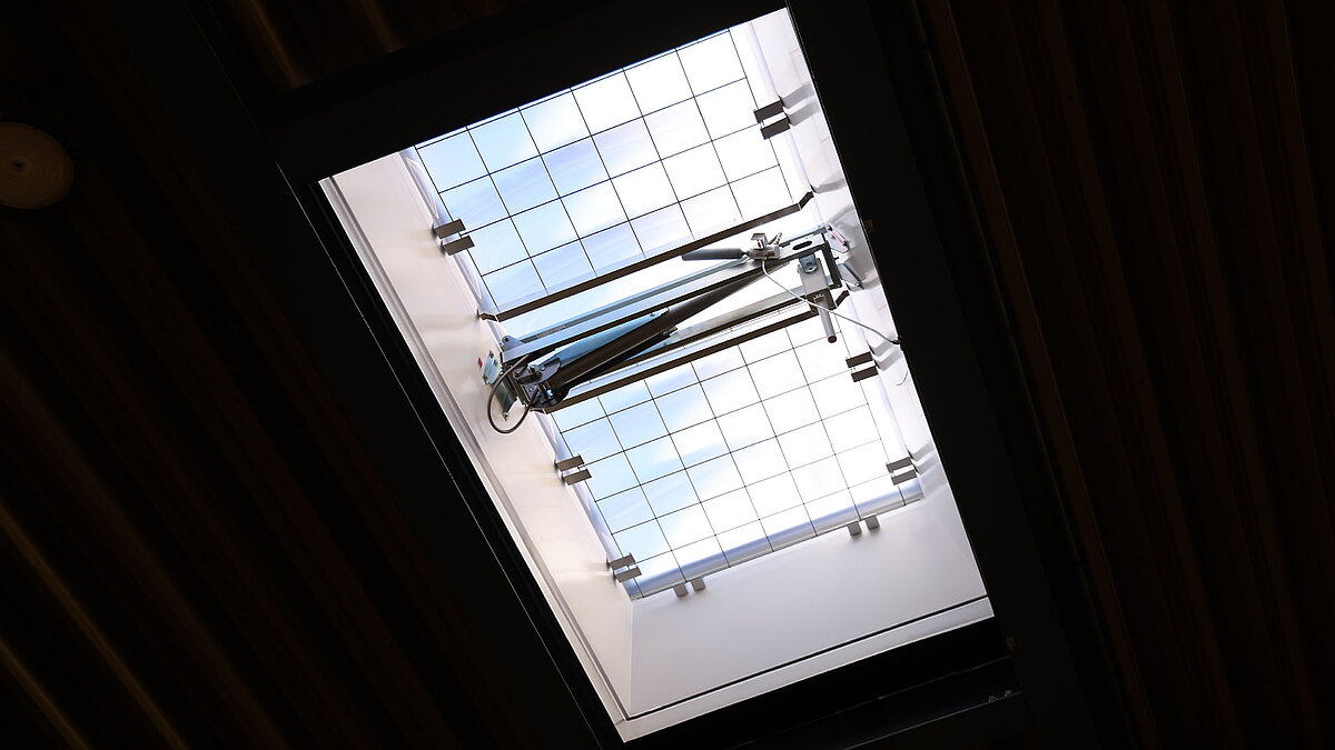 F100 W skylight with integrated fall-through protection grid in a warehouse, view from below into the roof opening