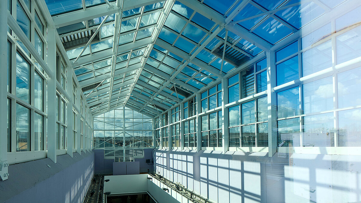 Interior view of a large glass roof with steel frame and glass walls in a modern building