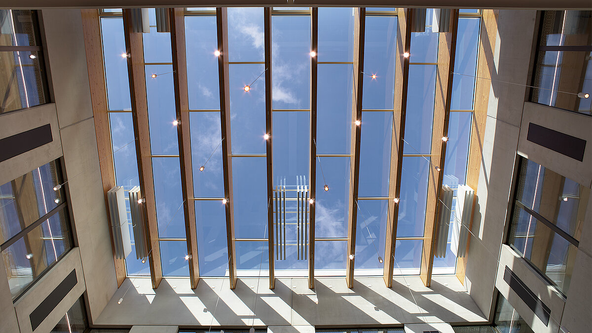 Modern atrium with vertical wooden slats and large glass roof with view of the sky