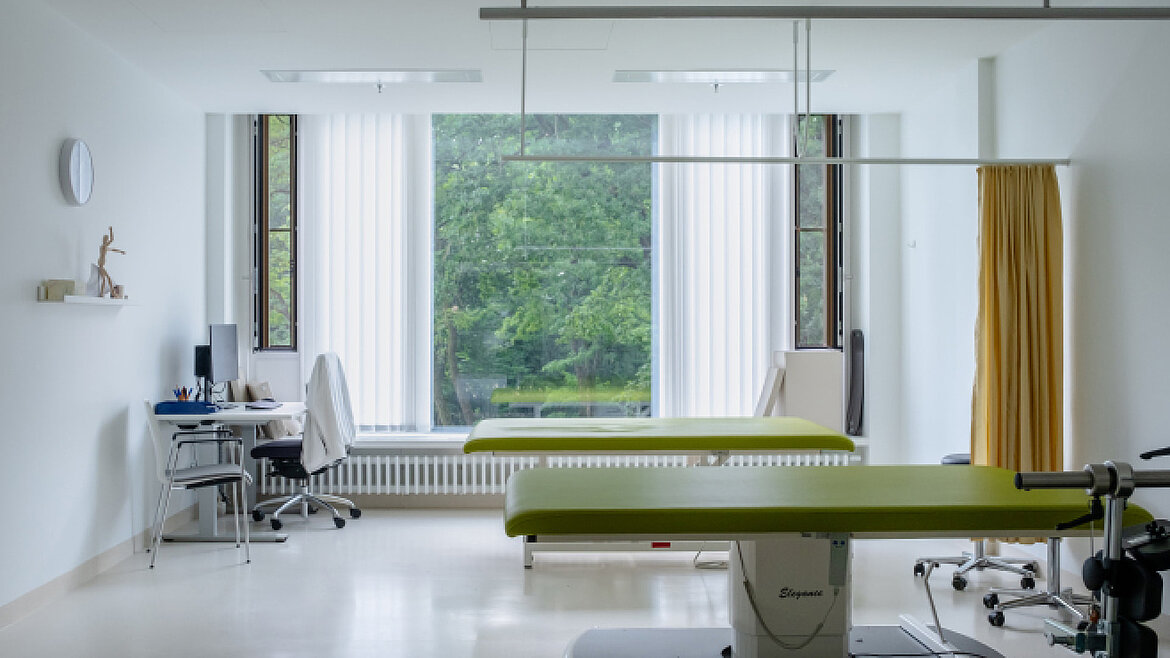 Bright treatment room with two couches and a large window overlooking greenery.