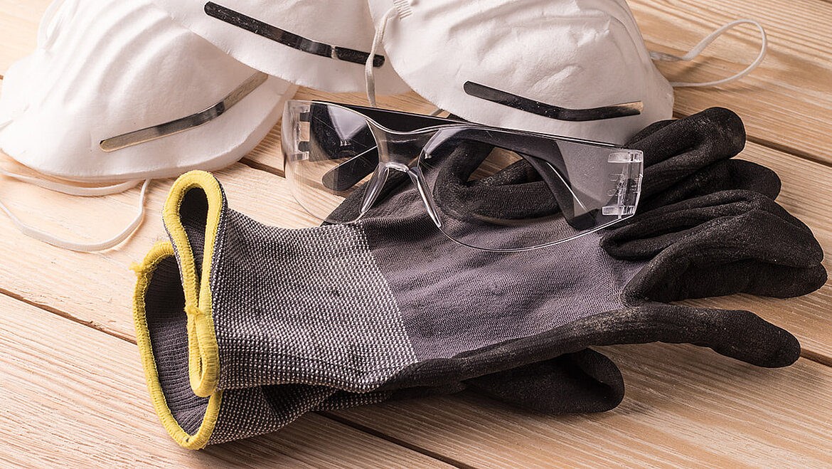 Gloves, safety goggles, and respiratory protection as safety clothing for roofers when waterproofing flat roofs with liquid plastic