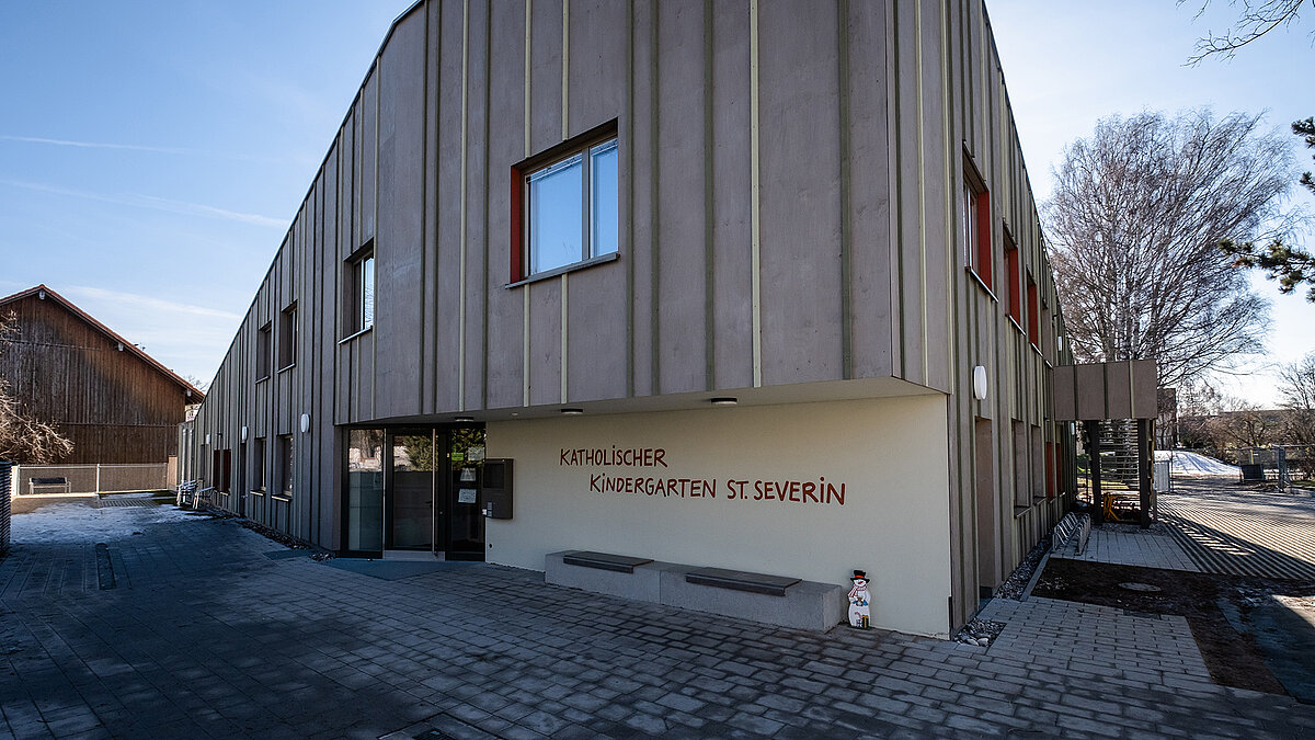 Exterior view of St. Severin Kindergarten with modern wooden facade and large windows.