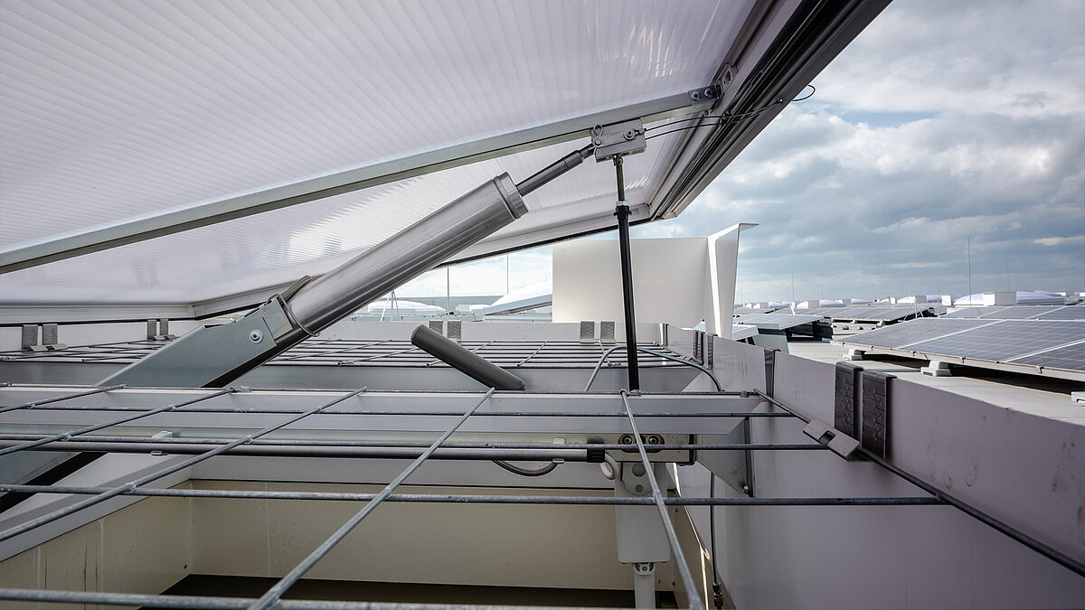Seitlicher Blick in eine geöffnete Lichtkuppel, bei der man den Öffnungsmotor und das Durchsturzgitter sieht