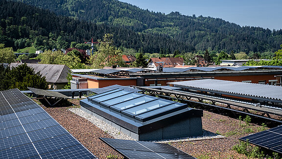 Modular glass roof from LAMILUX on a residential building in Freiburg, surrounded by solar panels and a green landscape.