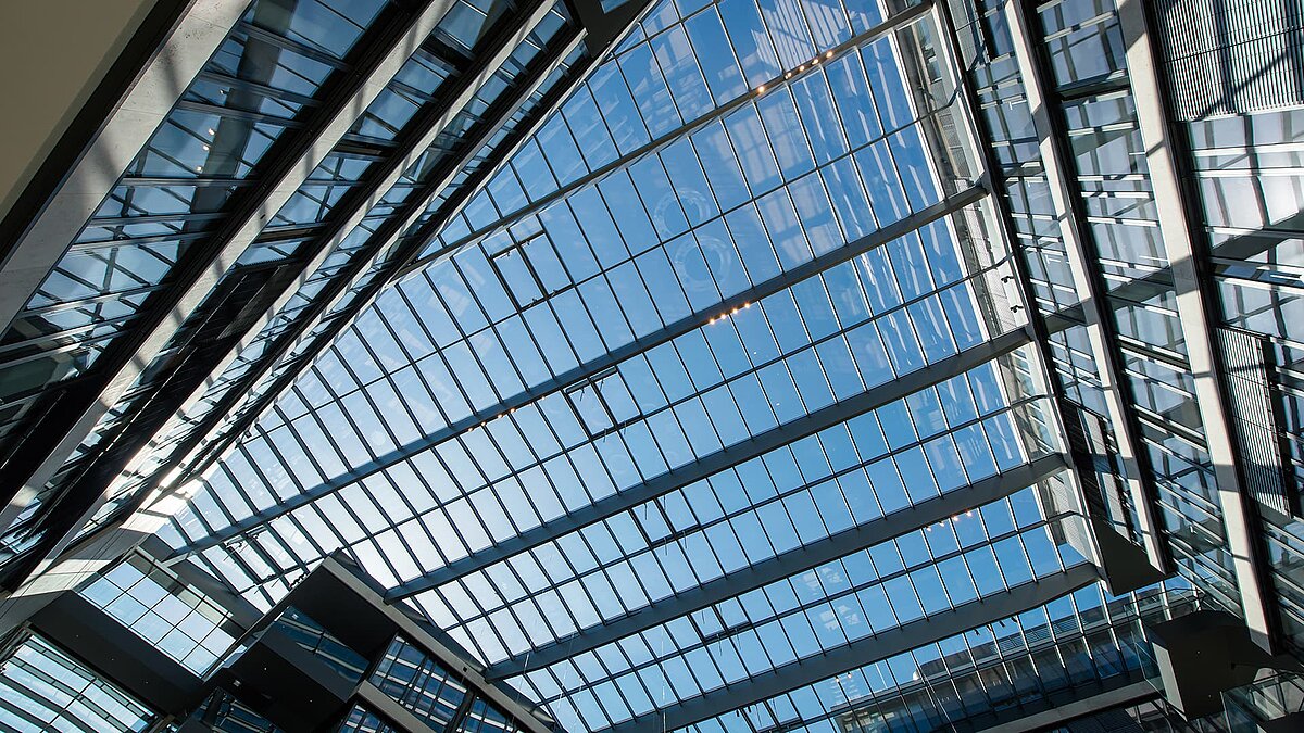 Modern glass roof at FGS Campus reflecting the sky and surrounding the sunlit atrium.