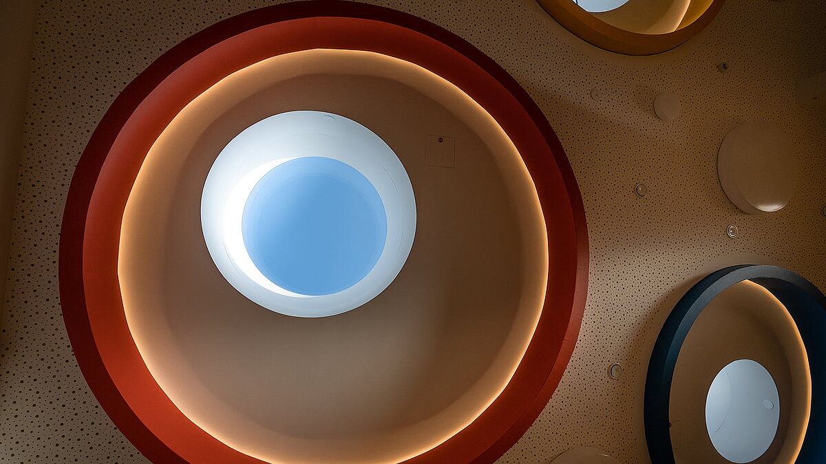 Close-up view of round skylights with colorful rings and indirect lighting in the "Glückliche Zukunft" daycare center in Sömmerda.