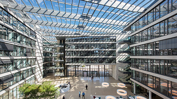 Spacious atrium of the FGS Campus with a glass roof, modern office buildings, natural light, and seating areas.