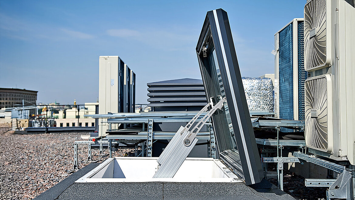 Openable roof window on flat roof with city buildings view