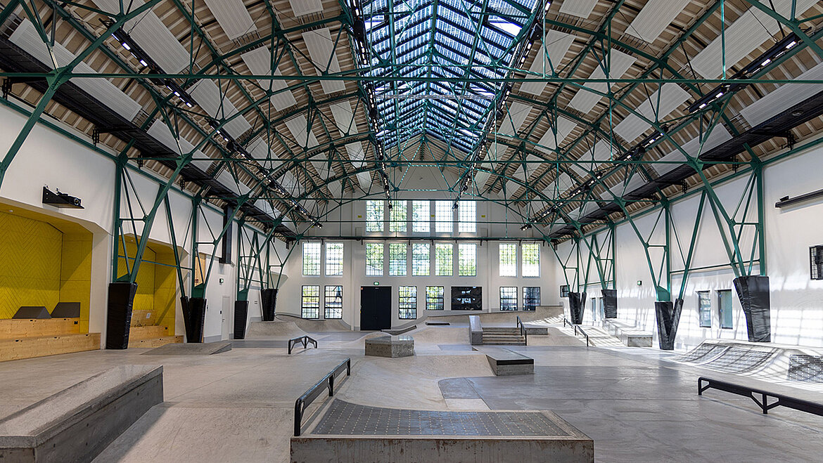 Modern indoor skate park with ramps, rails and steel beam roof structure