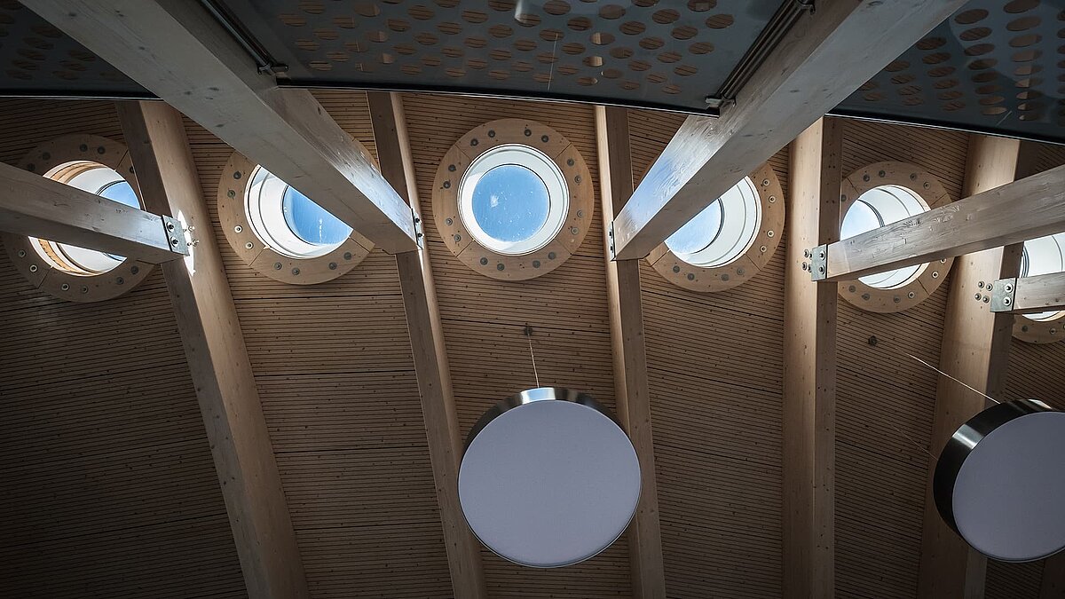 Interior view of the Norderney harbour terminal with round flat roof windows and wooden ceiling.