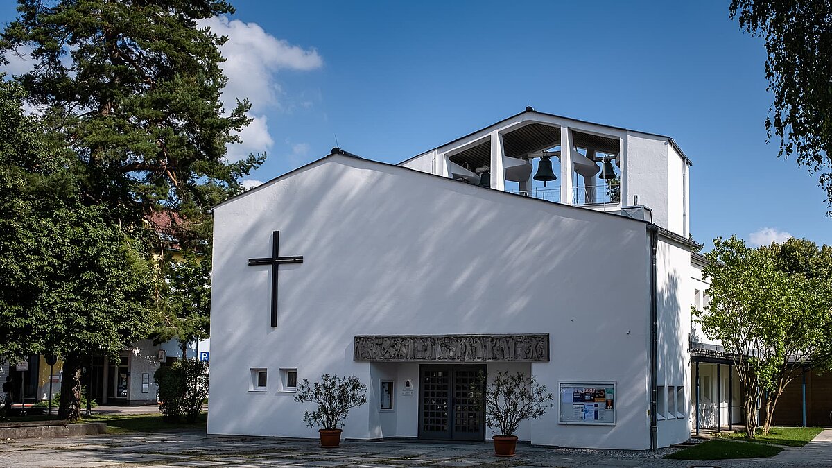 Modern Pauluskirche in Traunreut with white facade, large cross, and bell tower.