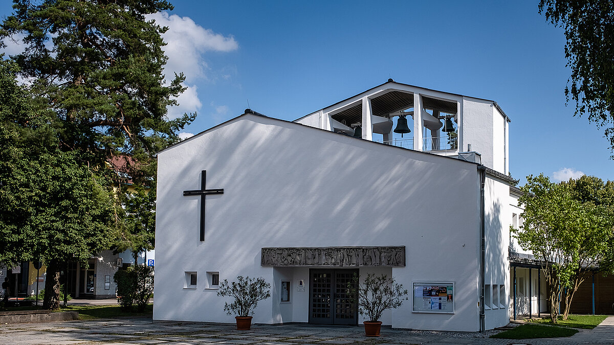 Modern Pauluskirche in Traunreut with white facade, large cross, and bell tower.