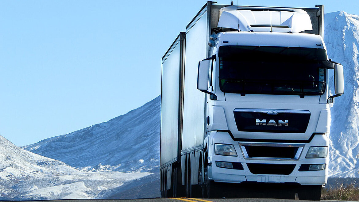White truck in front of a snowy mountain landscape
