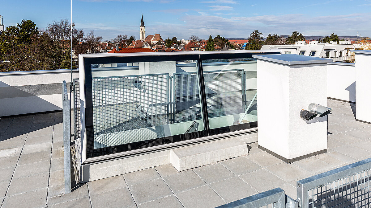 Flat roof access in a residential house in Korneuburg with modern glass design and a view of the city.
