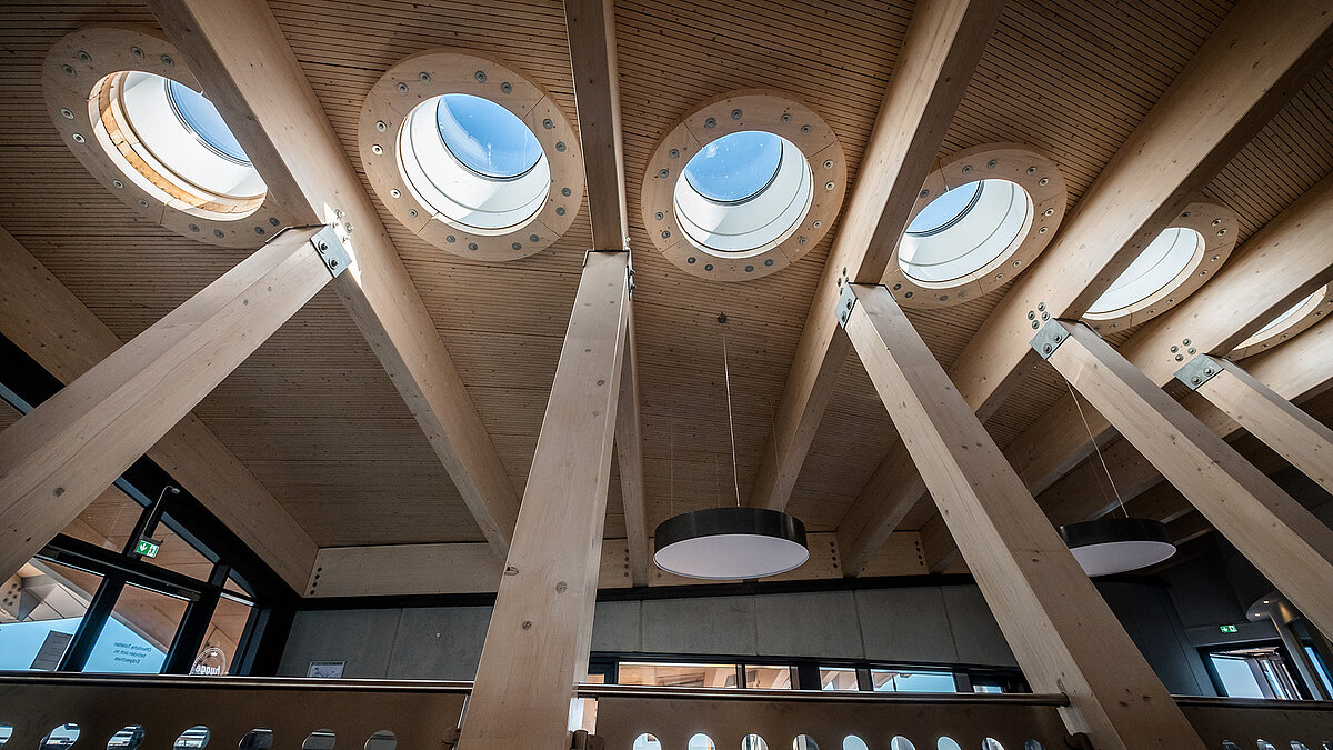 Interior view of the Norderney harbour terminal with several round flat roof windows and wooden beams.