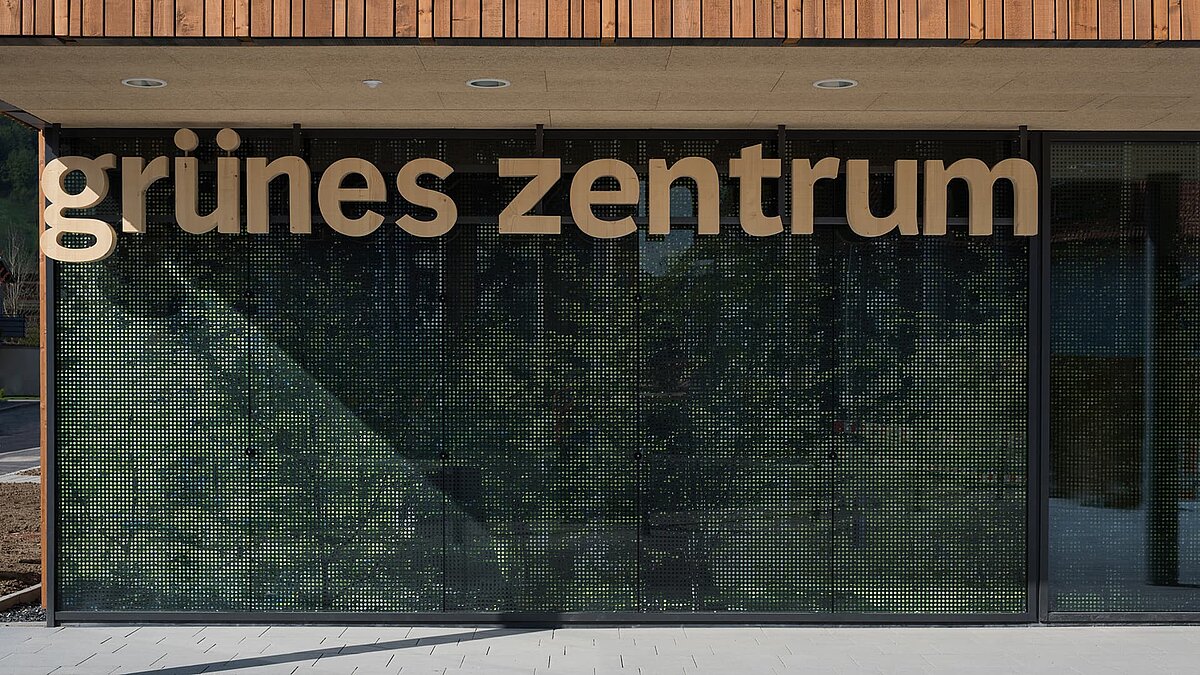 Entrance area of the Green Center Immenstadt with modern glass facade and wooden lettering.