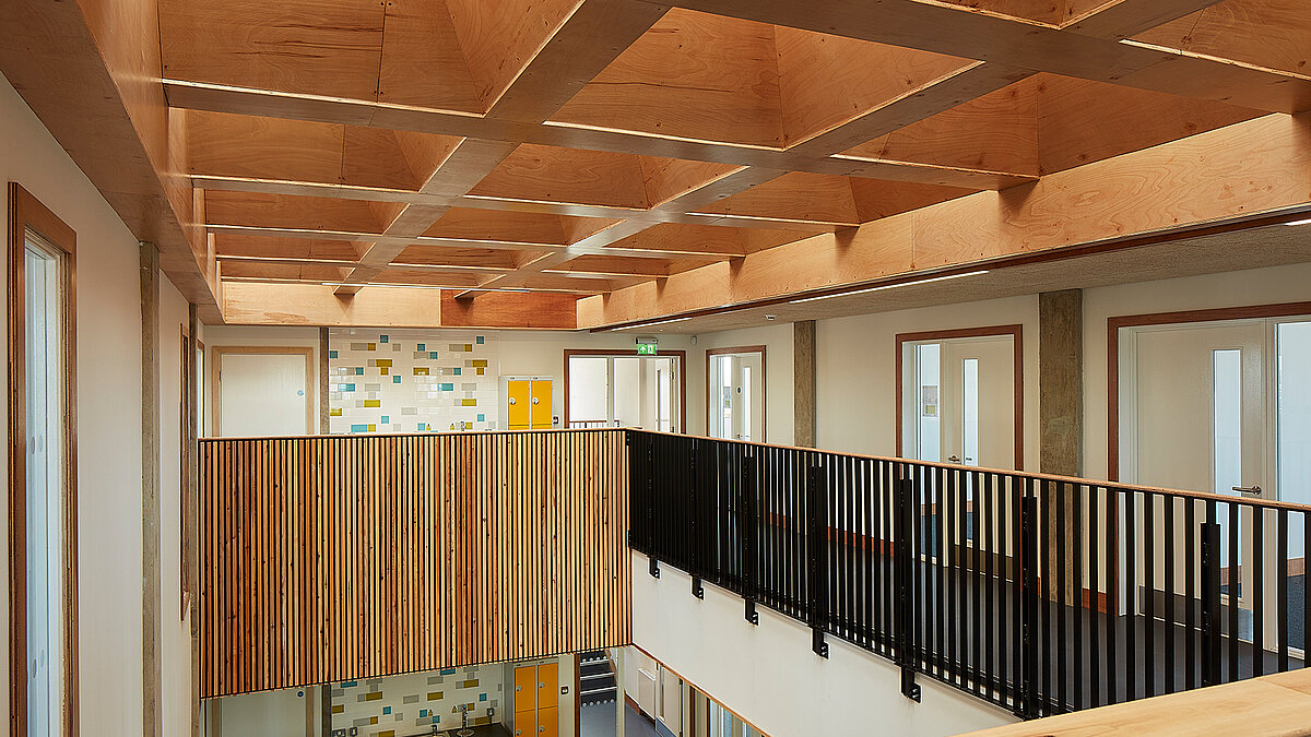 Bright upper floor with wooden ceiling structure, railing and modern interior design