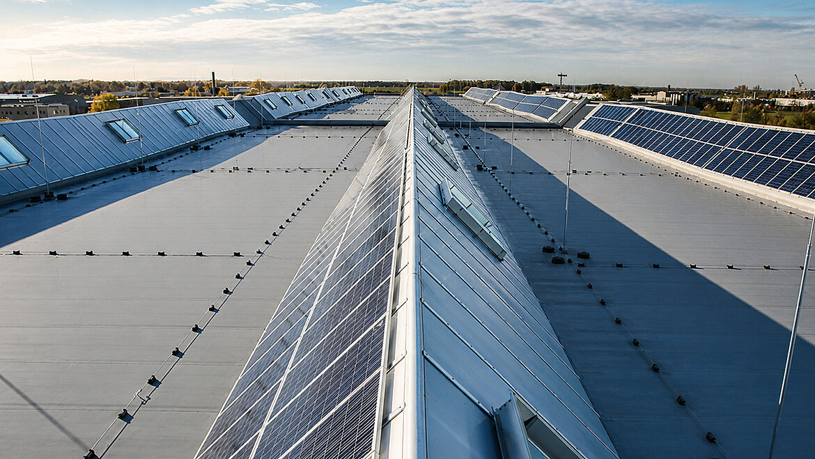 Industrial building with large-scale roof structure and installed solar panels under blue sky