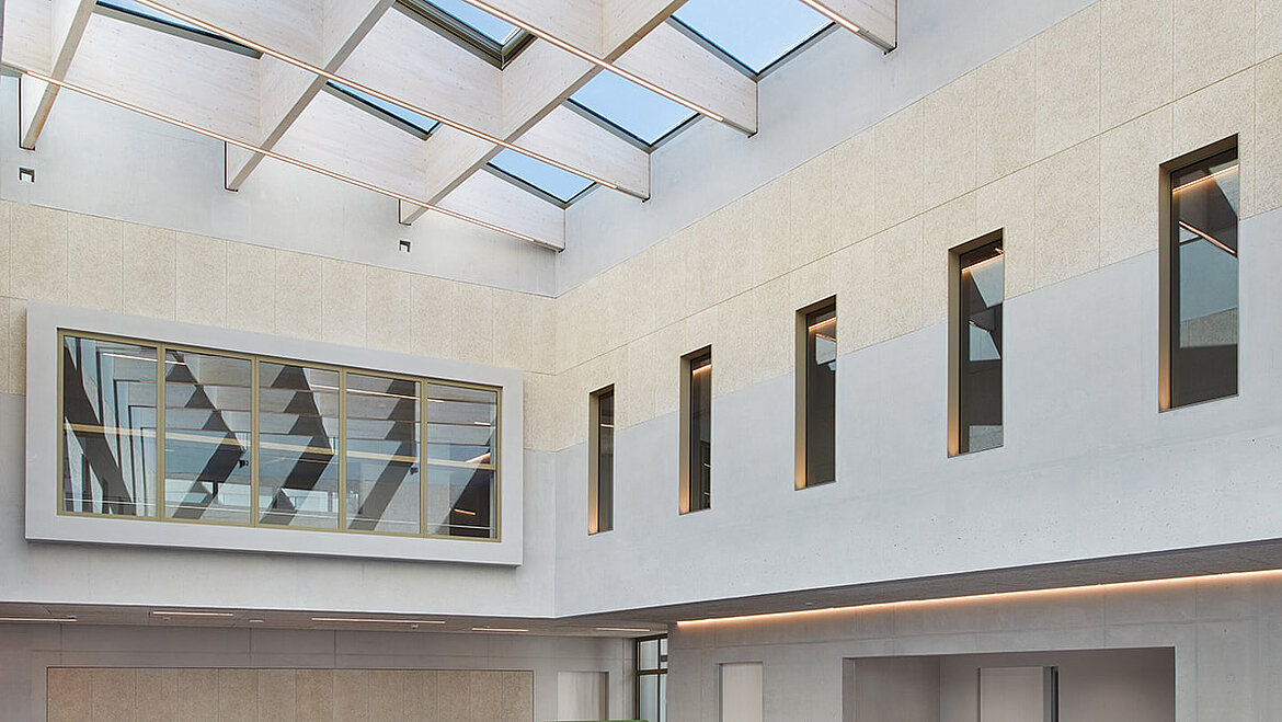 Bright atrium of a university with various windows and LAMILUX PR60 glass roof