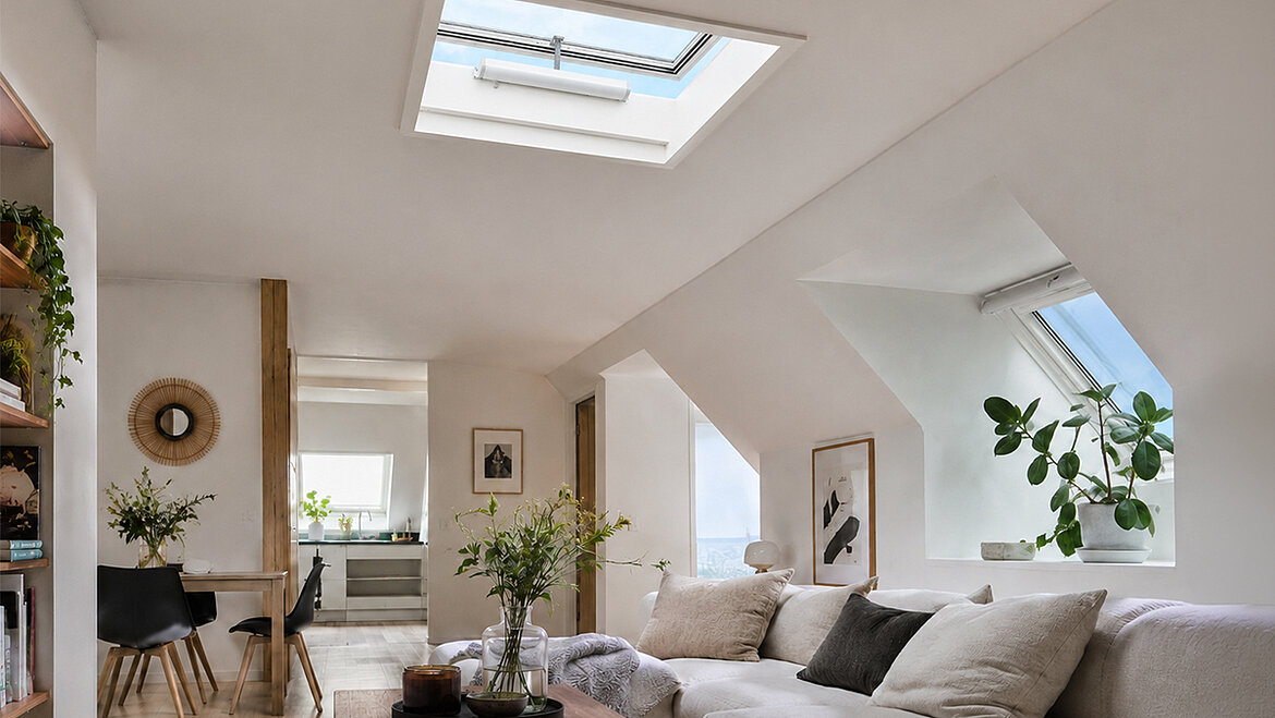 A bright living room with a white sofa, a wooden table and plants 