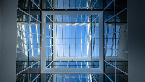 Upward view in the atrium of the Bertha-von-Suttner Realschule in Cologne featuring large glass panels and natural daylight.