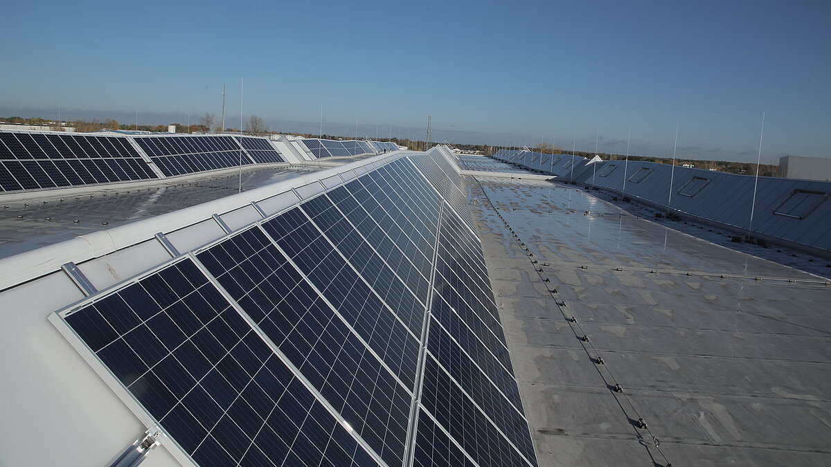 Roof of Rhenus Logistics logistics center in Hoppegarten featuring LAMILUX Lichtband S and solar panels.
