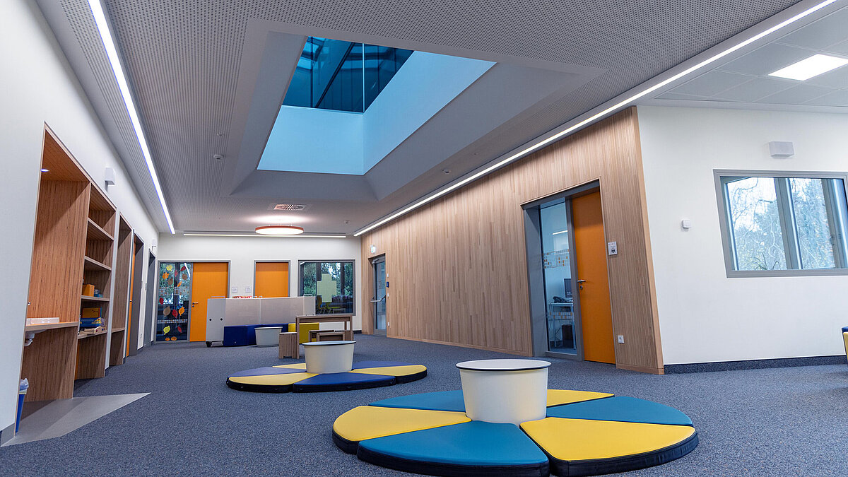 Corridor in Burgebrach school center with LAMILUX glass roof PR60 and colorful interior.