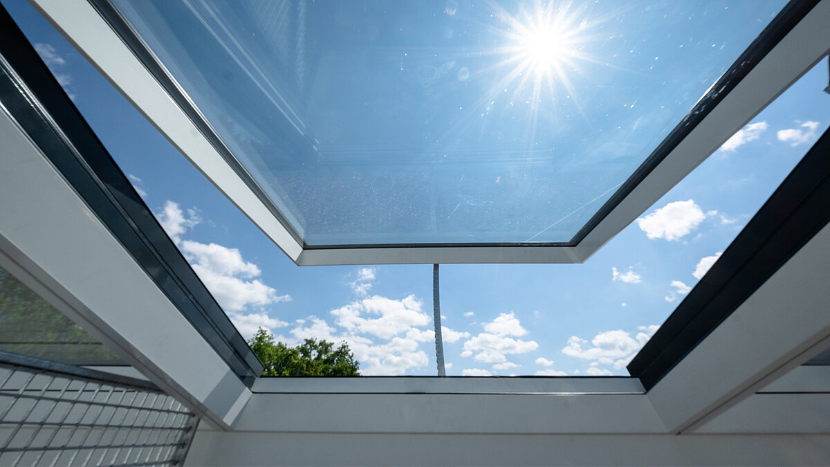 Residential building in Freiburg with modular glass roof from LAMILUX, view through the open roof into the sky.
