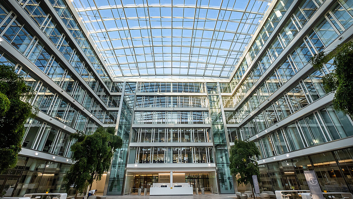 A bright atrium in a modern office building with a large glass roof