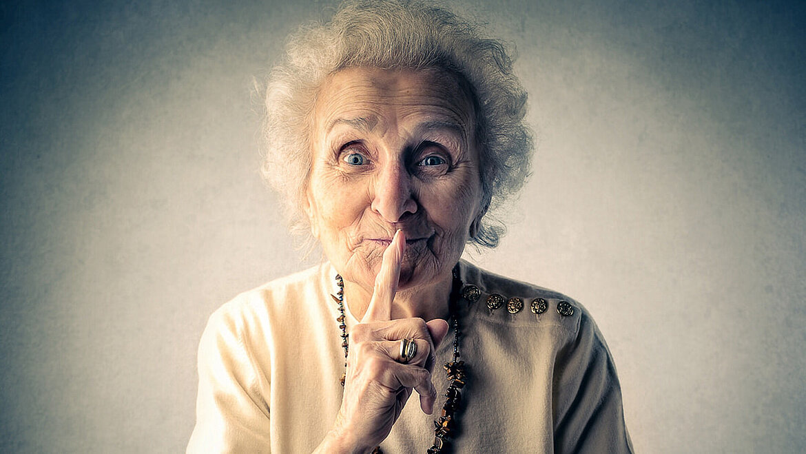 Old woman shows gesture of silence Grandma has fingers in front of her mouth and keeps a secret | insights by LAMILUX