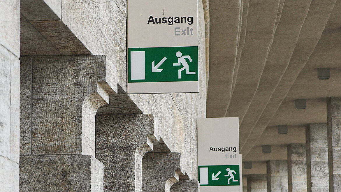 Escape plans are one of the organisational measures of preventive fire protection. Emergency exit shows way out of building | insights by LAMILUX