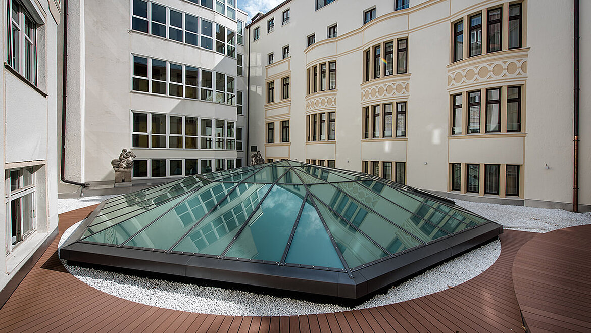 Glass pyramid with ventilation sash on the lobby roof of the Hotel Vier Jahreszeiten in Munich Individually designed LAMILUX PR60 glass roof pyramid between hotel buildings | insights by LAMILUX