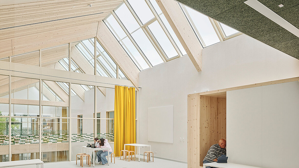 Bright interior featuring timber ceiling, glass roof lantern, yellow curtains and people at tables