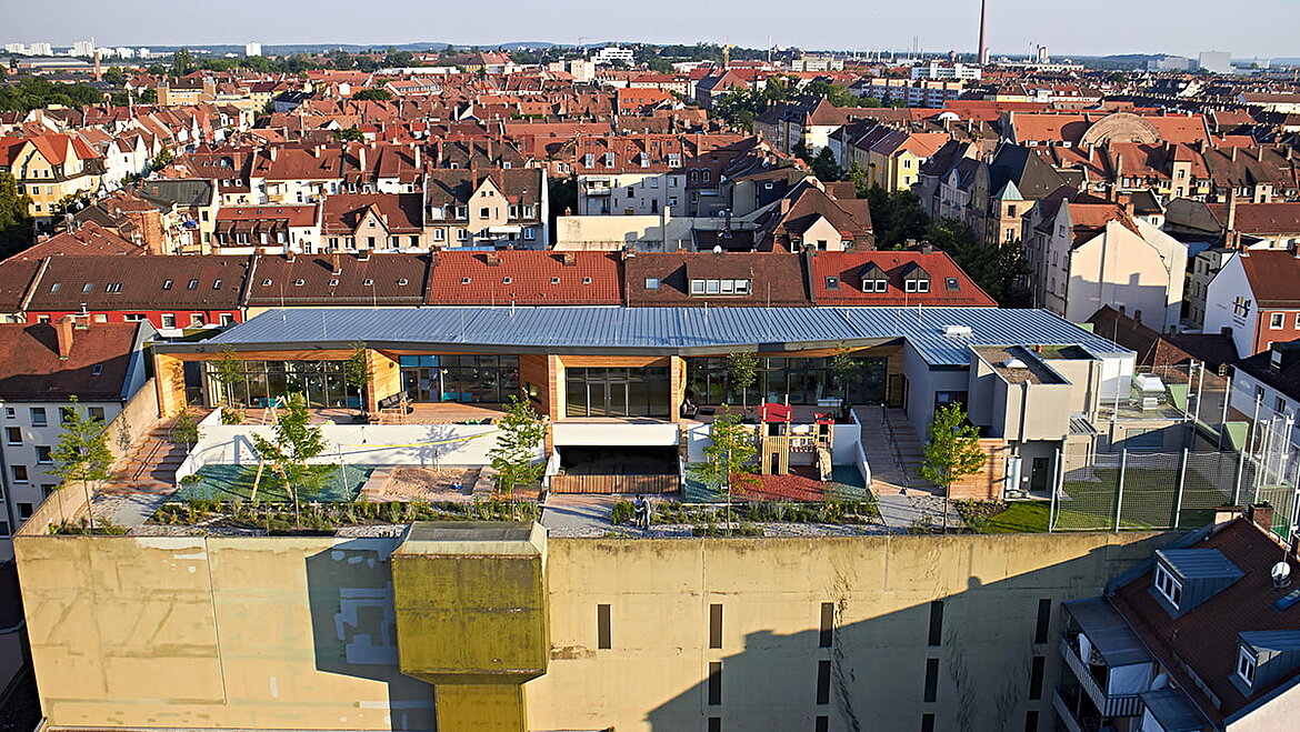 The exterior view of the daycare centre "Wolke 10" in Nuremberg View over the roofs of Nuremberg and the outdoor area of the "Wolke 10" daycare centre on the roof of a parking garage | insights by LAMILUX